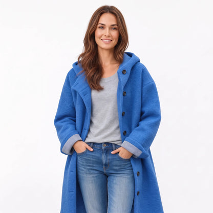 Studio view of a model in the bright blue hooded coat with dark buttons and striped cuffs 17