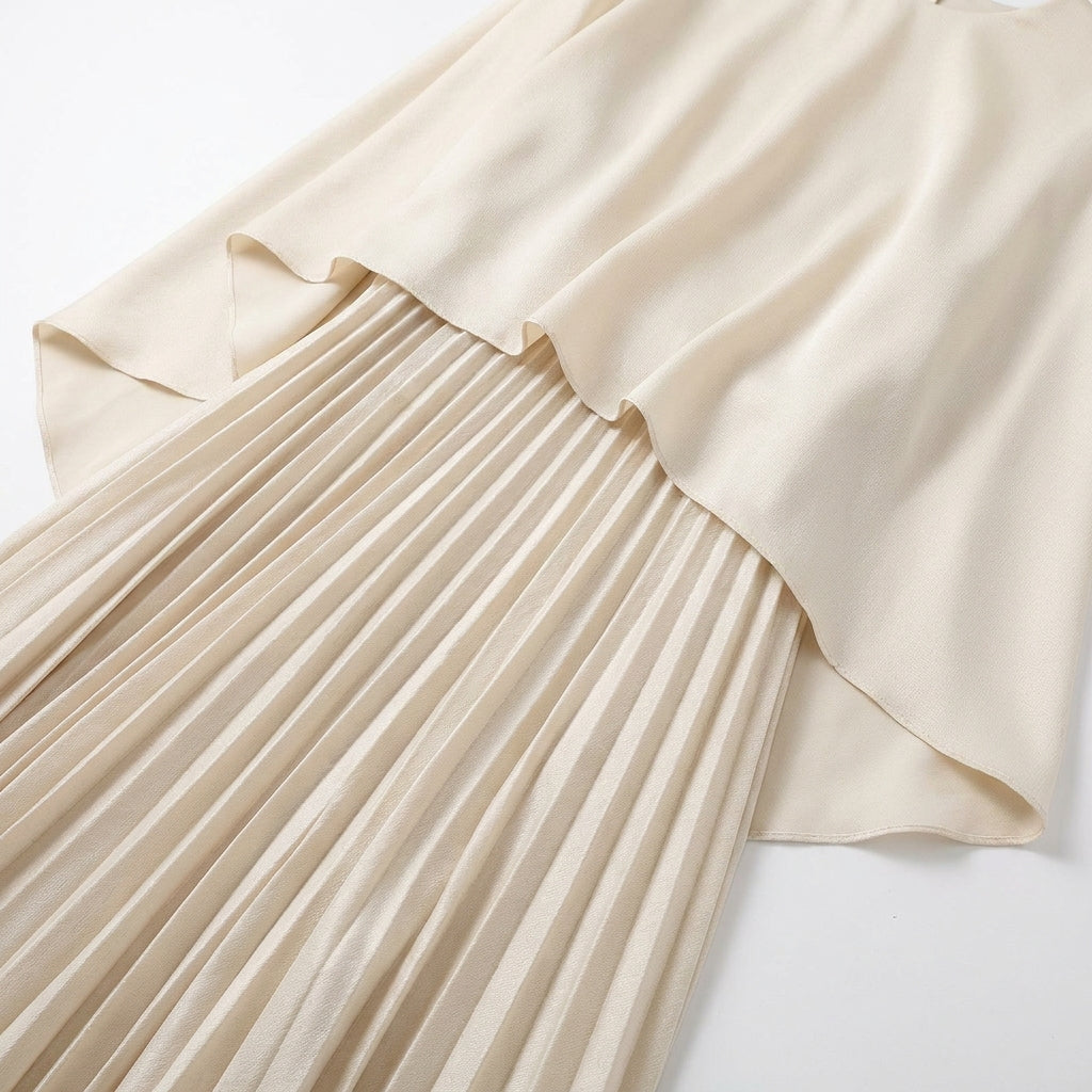Flat lay detail of the cream cape top's curved hem falling over the fine pleated skirt 4