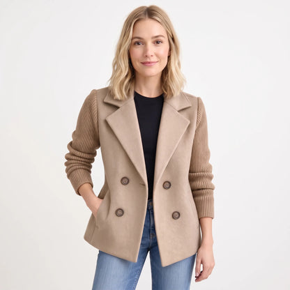 Studio shot of model in camel double-breasted jacket with ribbed knit sleeves, black top and jeans 18