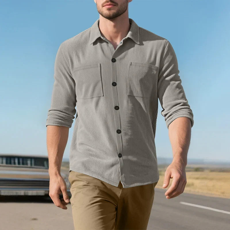 Model walking outdoors in the grey ribbed shirt with sleeves rolled, under a blue sky 18