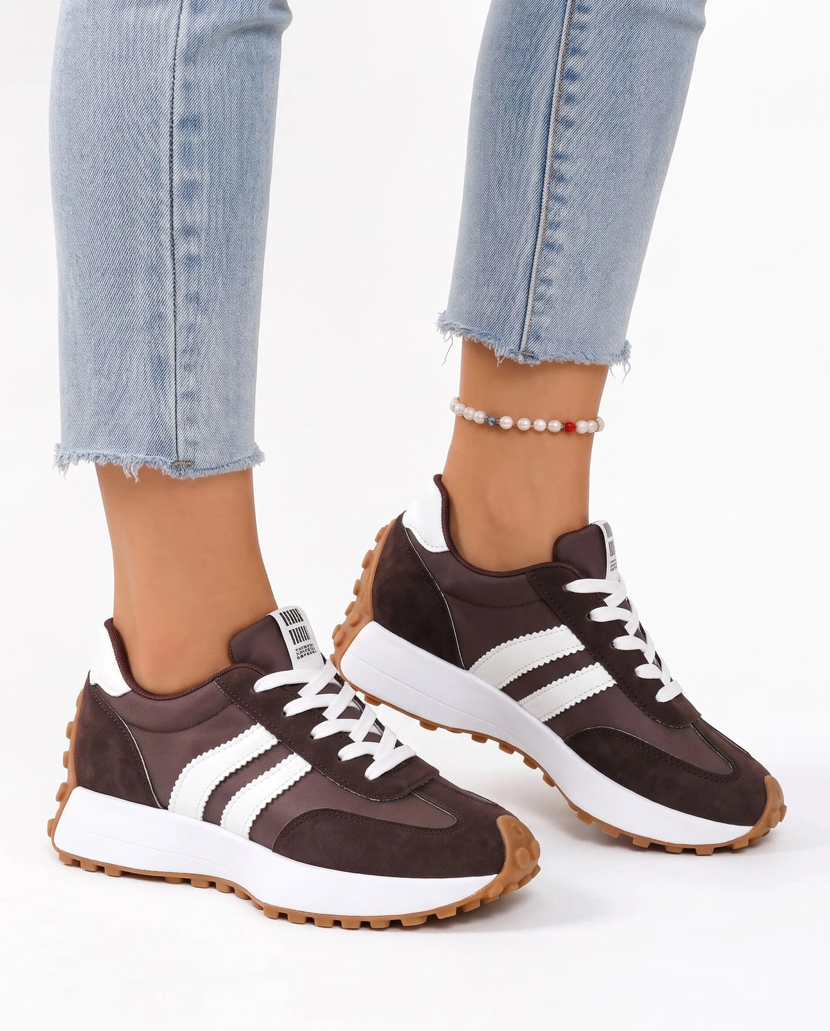 Brown suede and nylon trainers with white stripes and gum soles, worn with light blue jeans and a pearl anklet 18