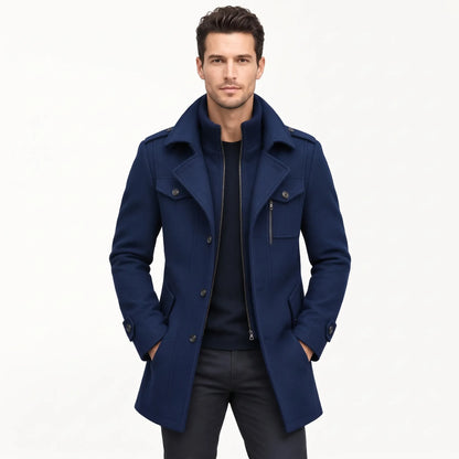 Man wearing the navy coat open over a dark jumper and black trousers, hands in pockets 19