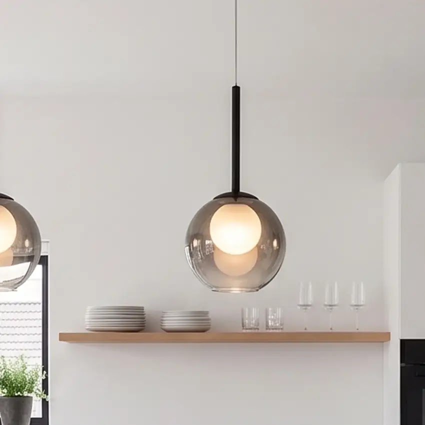 Close view of a smoke grey globe pendant glowing above a wooden shelf holding plates and glasses 11