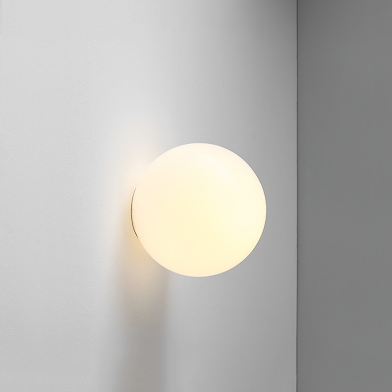 Close-up of a single lit opal glass sphere fixed to a grey wall, glowing warm white 16