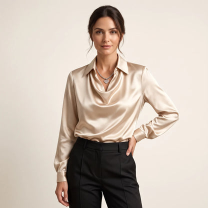 Model in a champagne satin blouse with draped collar, black trousers and heart pendant necklace, hand on hip 1
