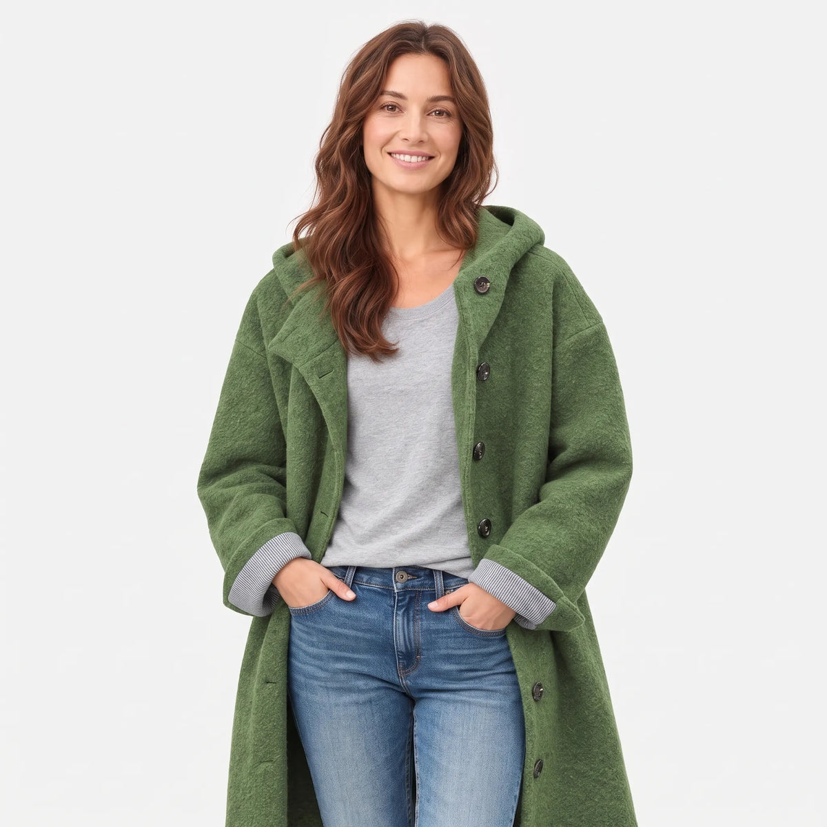 Close studio view of a model in the green textured coat, striped cuffs turned back, hands in jeans pockets 1