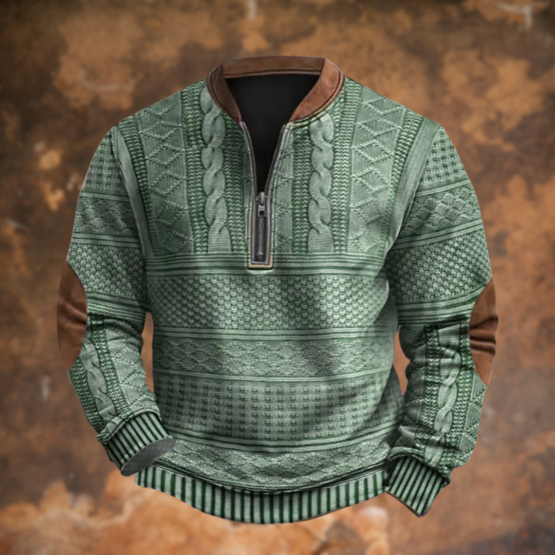 Front view of the sage green version with cable and diamond knit panels, brown collar trim, half zip and tan elbow patches, on a rusty backdrop. 6