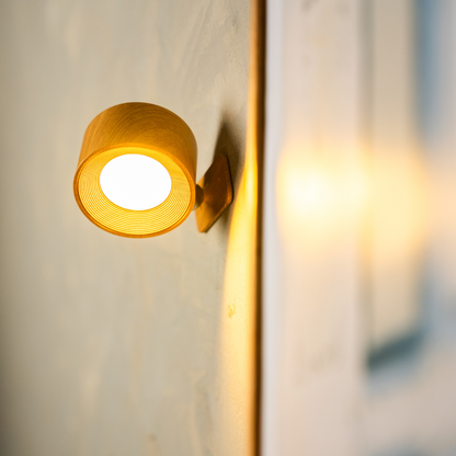 Close-up of the wood-effect wall light lit, showing the ribbed inner ring and the round diffuser. 15