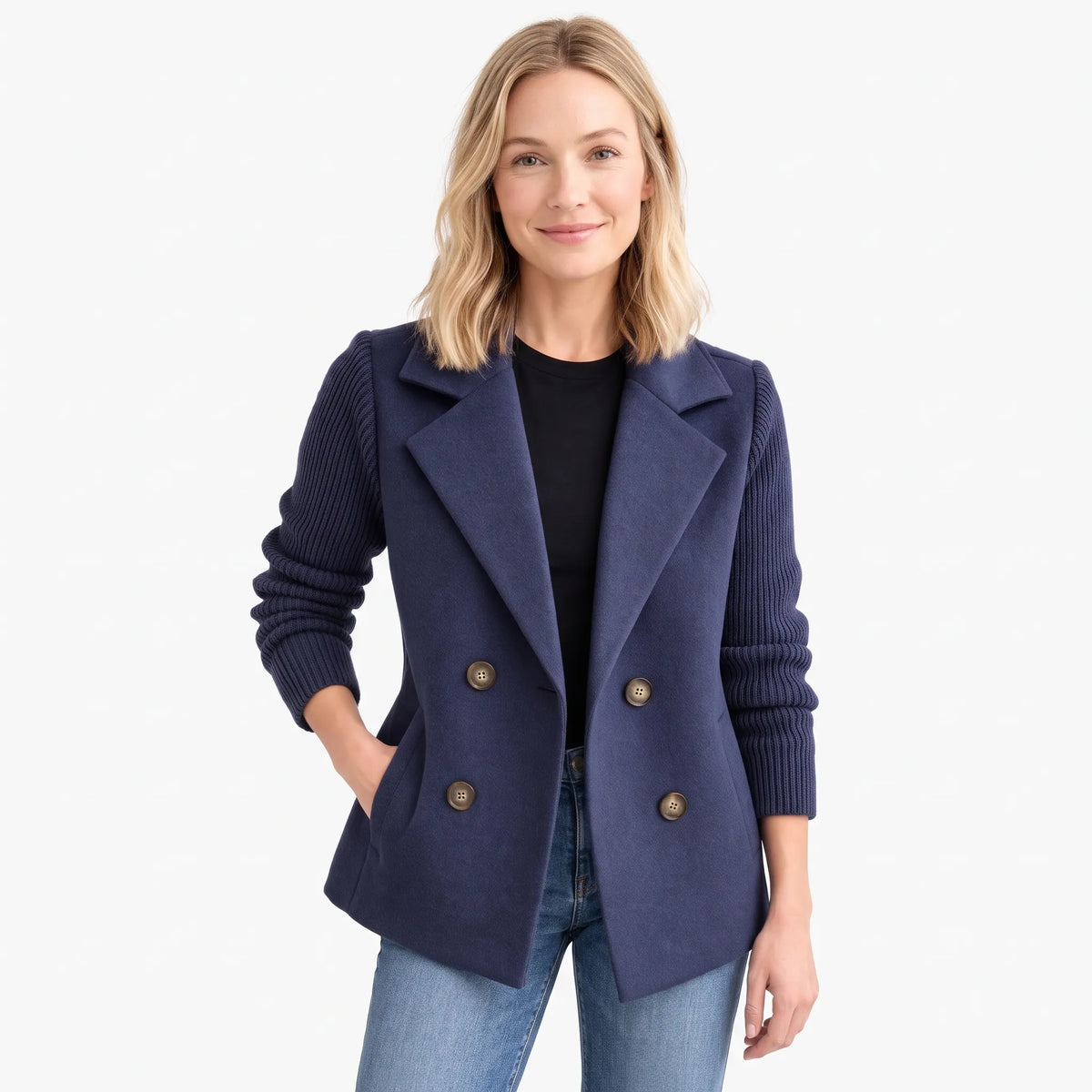 Model in navy double-breasted jacket with ribbed knit sleeves, one hand in pocket, studio background 1