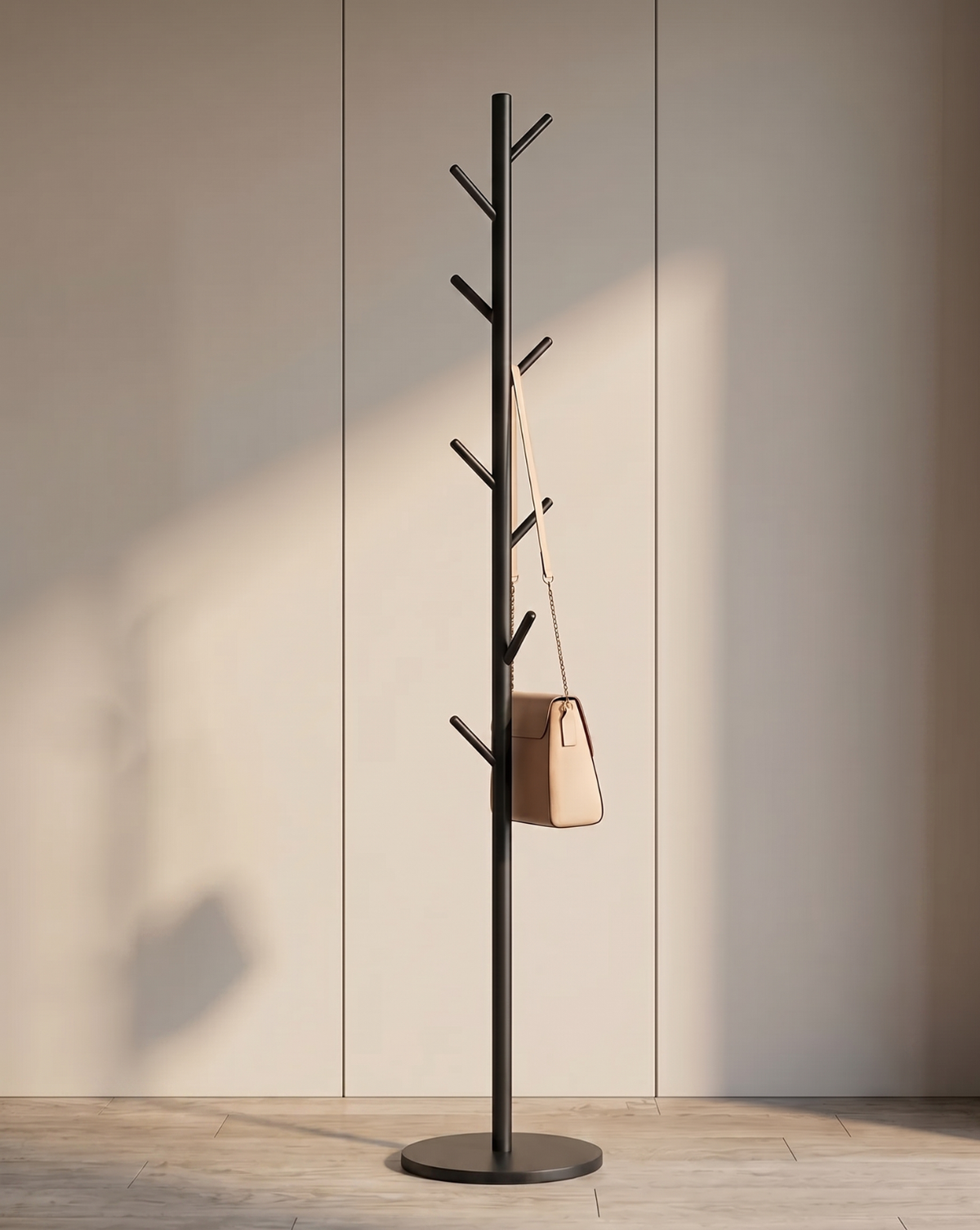 Black coat rack standing against a panelled wall, with a beige shoulder bag hanging from one of its angled hooks. 1