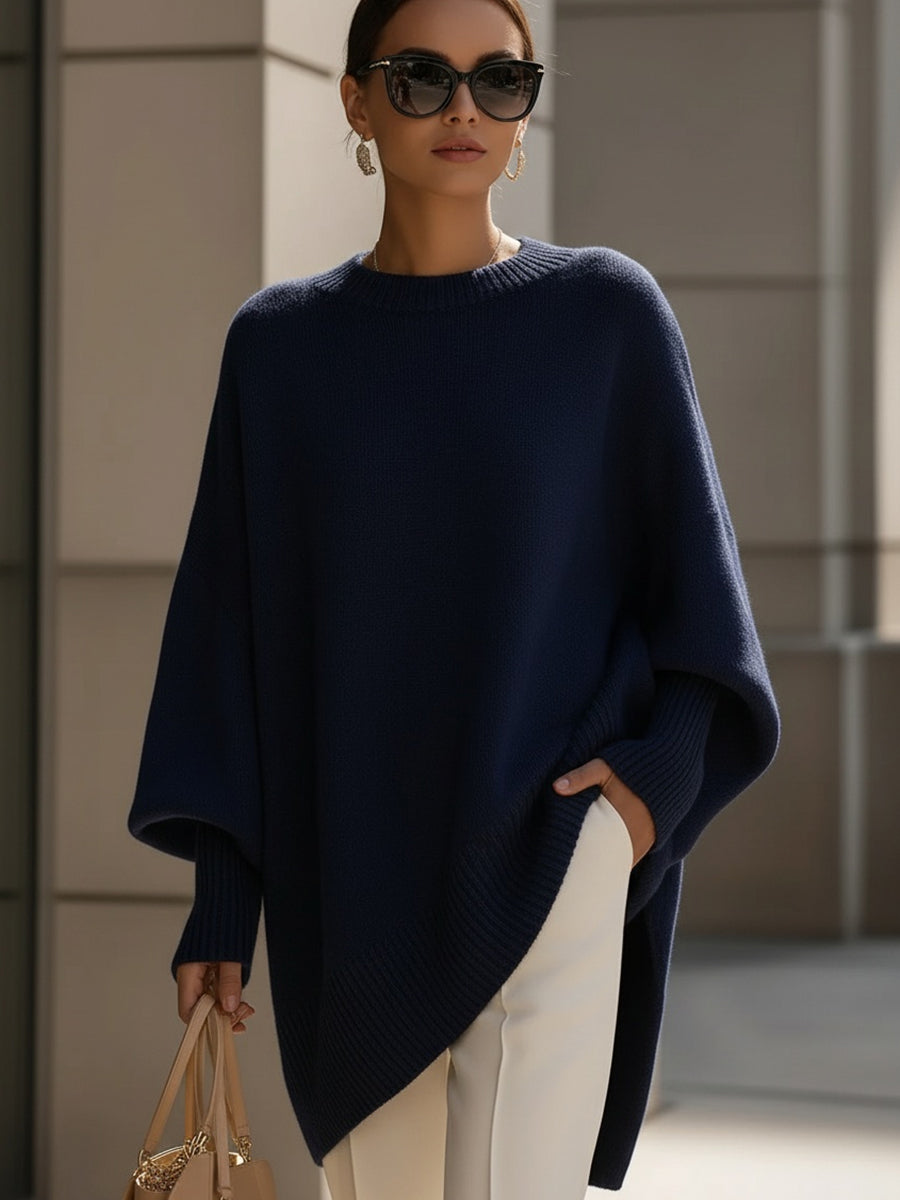 Navy blue version of the knit poncho, styled with white trousers, sunglasses and a handbag 9