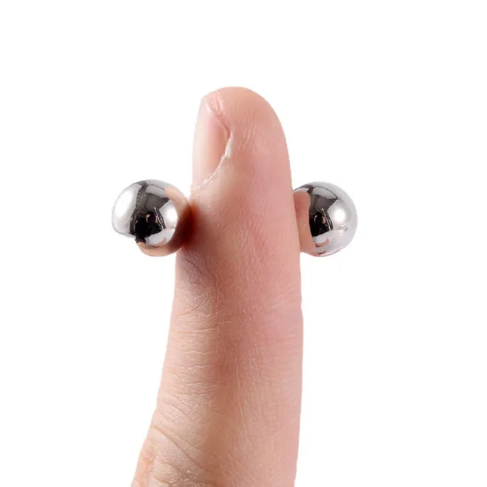 Fingertip held upright with a silver magnetic ball on each side, clamped through the skin by magnetic attraction alone, to show how they grip. 7
