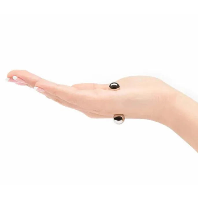 Open palm viewed from the side with two silver magnetic balls held on opposite sides of the hand, showing how they attach. 9