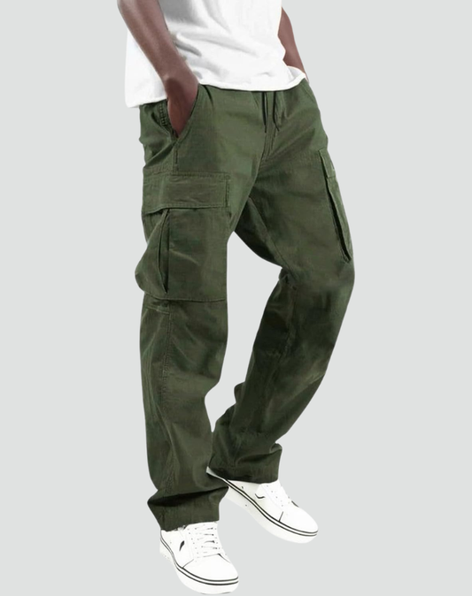 Model in olive green cargo trousers, white t-shirt and trainers, one hand in a pocket, seen from the side. 1