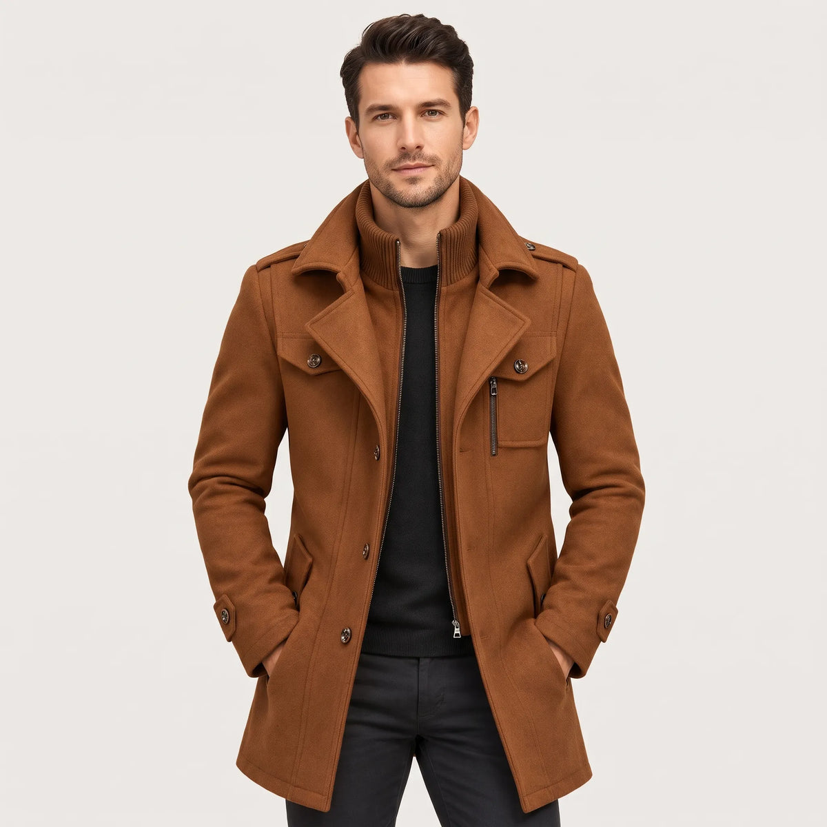 Man wearing the tan coat open over a black jumper, hands in pockets 1