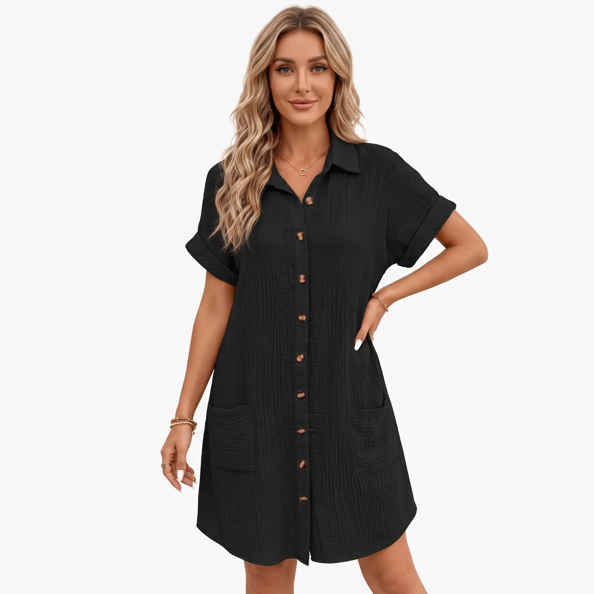 Model in black crinkled shirt dress with buttons and pockets, one hand on hip, studio background 1