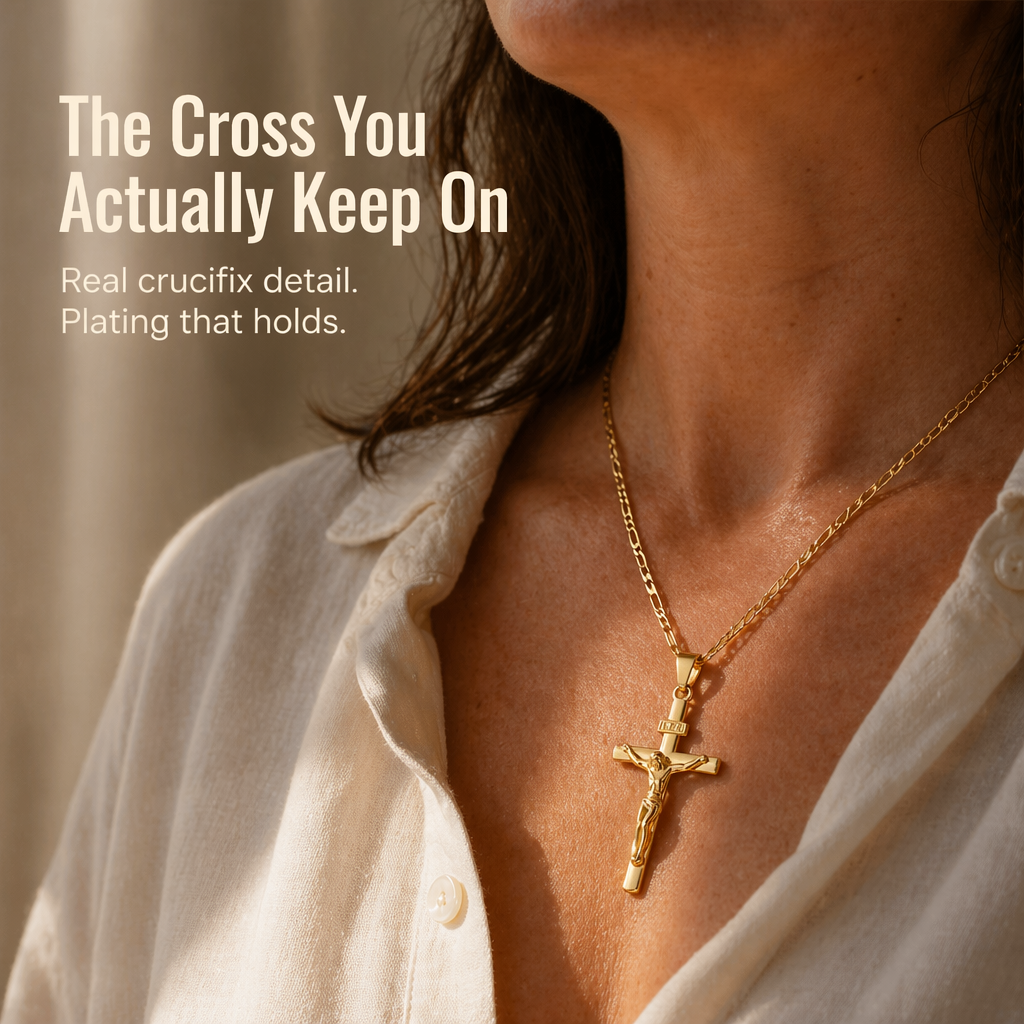 Close-up of a woman wearing the gold crucifix on its Figaro chain with an open cream linen shirt 1