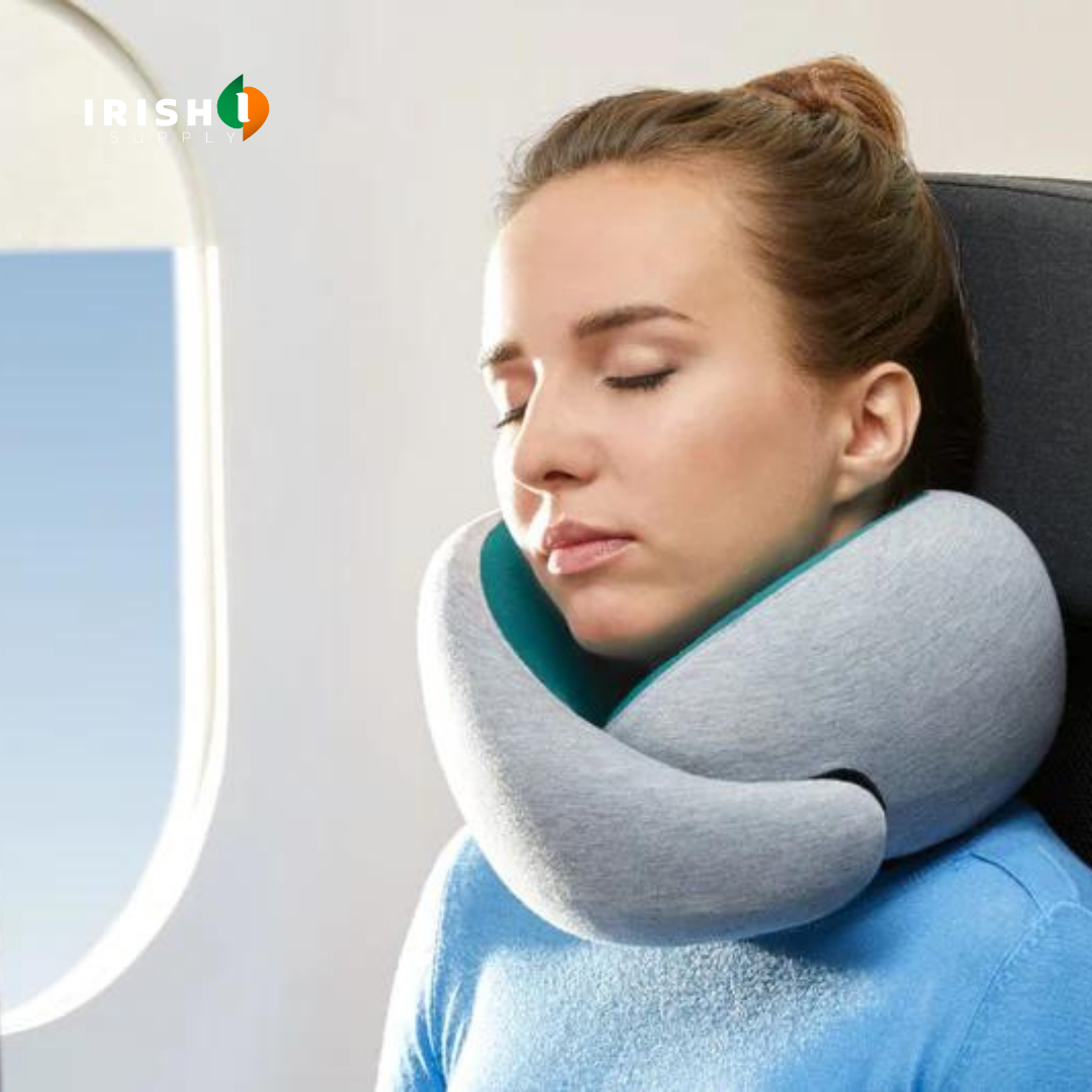 Woman with eyes closed sleeping beside an aeroplane window, her chin resting on a grey neck pillow with a teal lining. 1