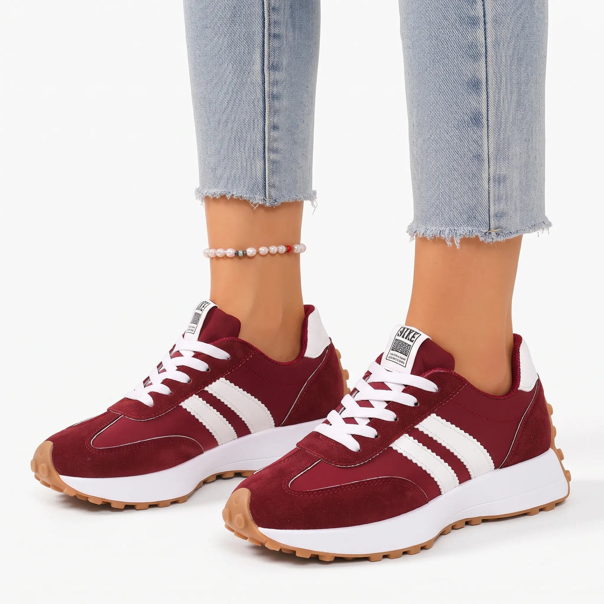 Burgundy suede and nylon trainers with white side stripes and gum sole, worn with cropped jeans 1
