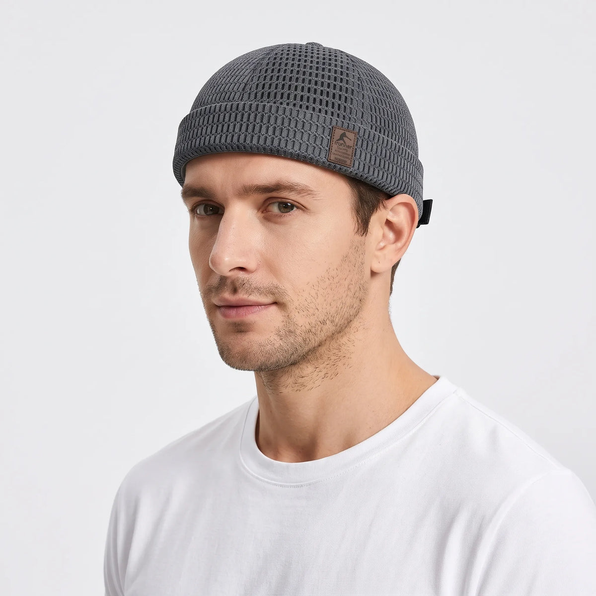 Man in a white t-shirt wearing the grey open weave brimless cap, three-quarter view 1