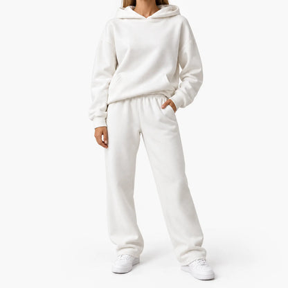 Model in a cream hooded sweatshirt and straight-leg joggers, one hand in pocket, with white trainers 1
