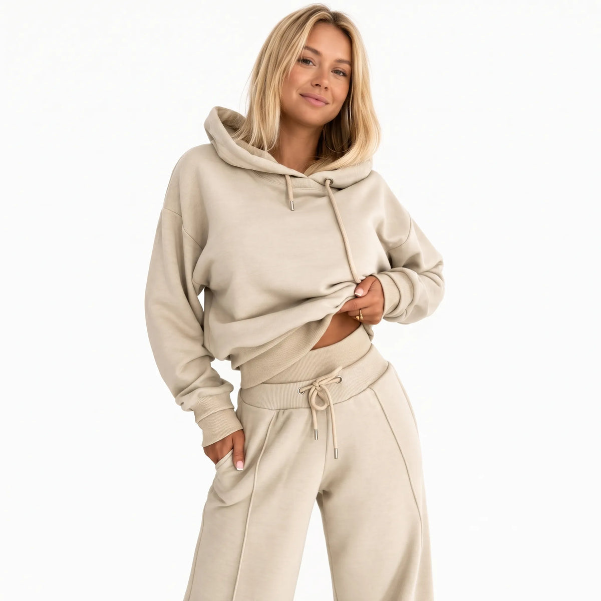 Model in a beige hooded sweatshirt and wide-leg joggers, posed against a plain white background 1