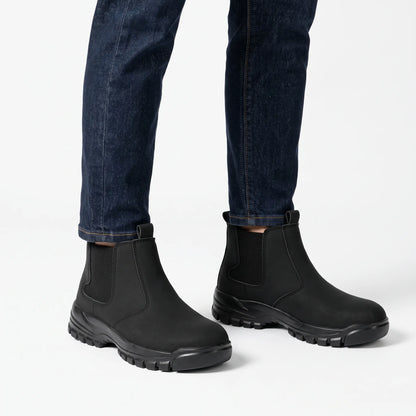 Black slip-on boots worn with dark indigo jeans against a plain white studio background 1