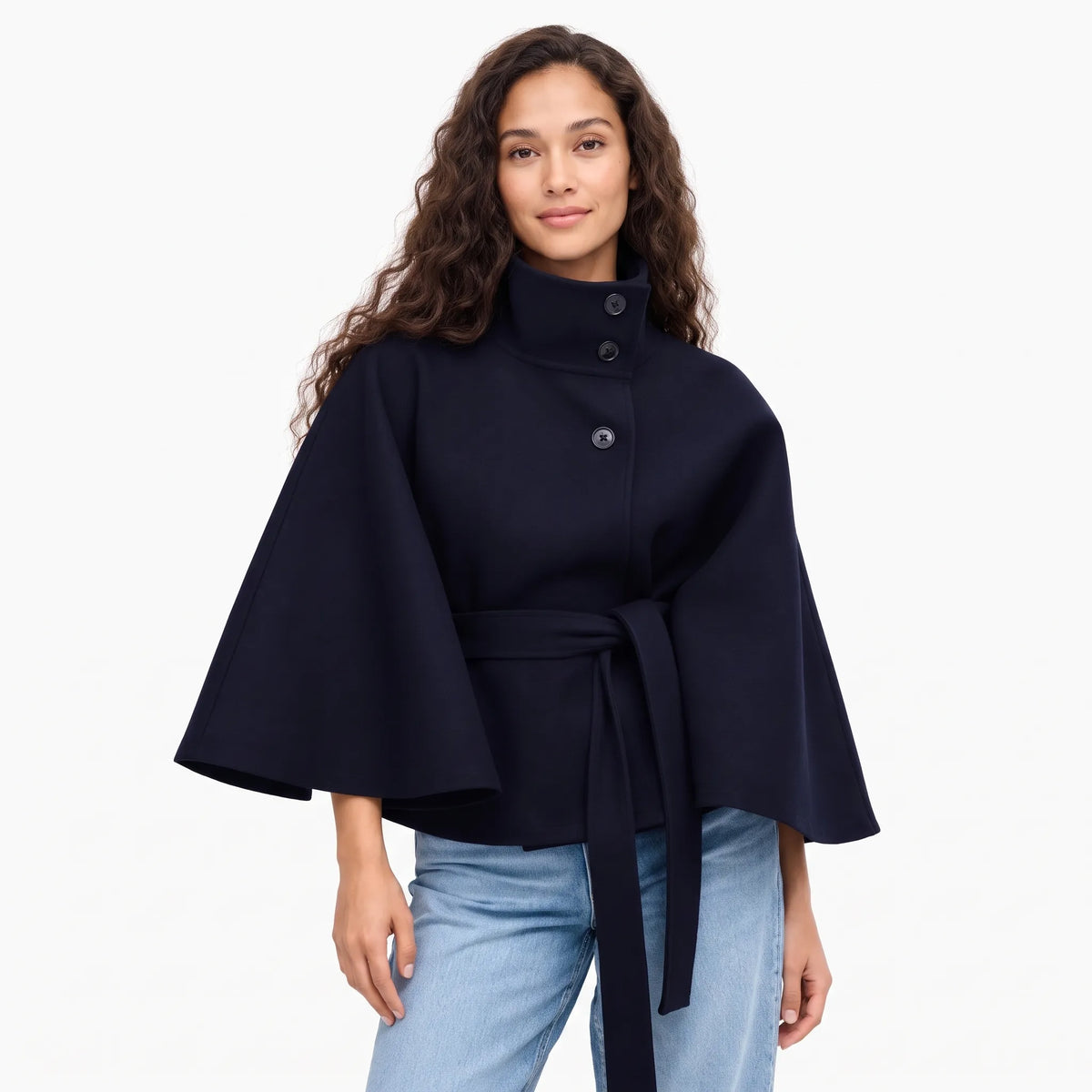 Model with long wavy hair wears the navy cape jacket with jeans, front view, tied belt 1