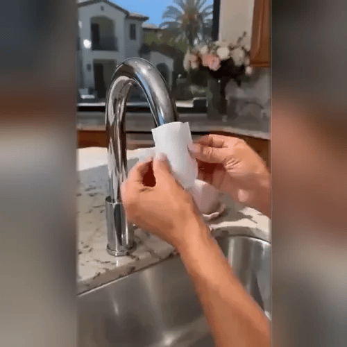 Hands holding a flat white filter cover up to the spout of a curved chrome kitchen tap. 2
