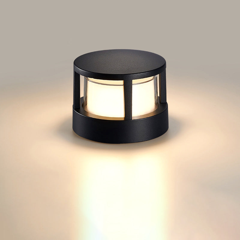 Round black light with solid flat top and frosted white shade glowing warmly on a plain neutral background. 8