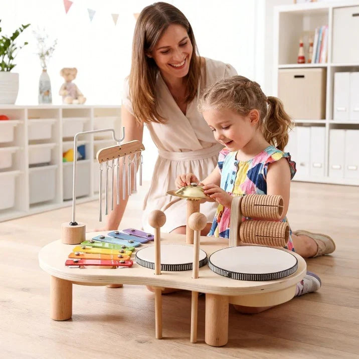 Mother and young daughter kneel at the table, the girl tapping the small brass cymbal 5