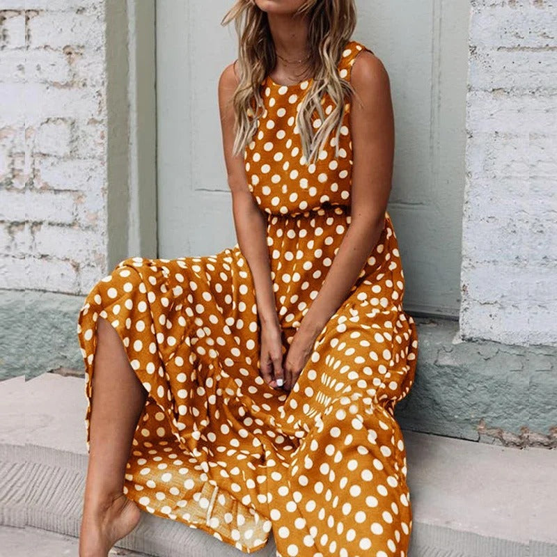 Woman sitting on a stone step wearing the mustard yellow polka dot dress, with its gathered waist and flowing skirt. 3