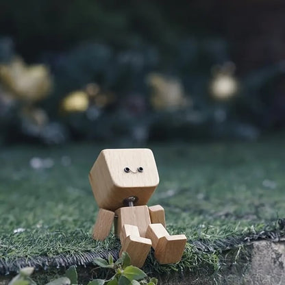 Wooden figure with a smiling face sitting on a patch of artificial grass, with blurred garden decorations behind. 5