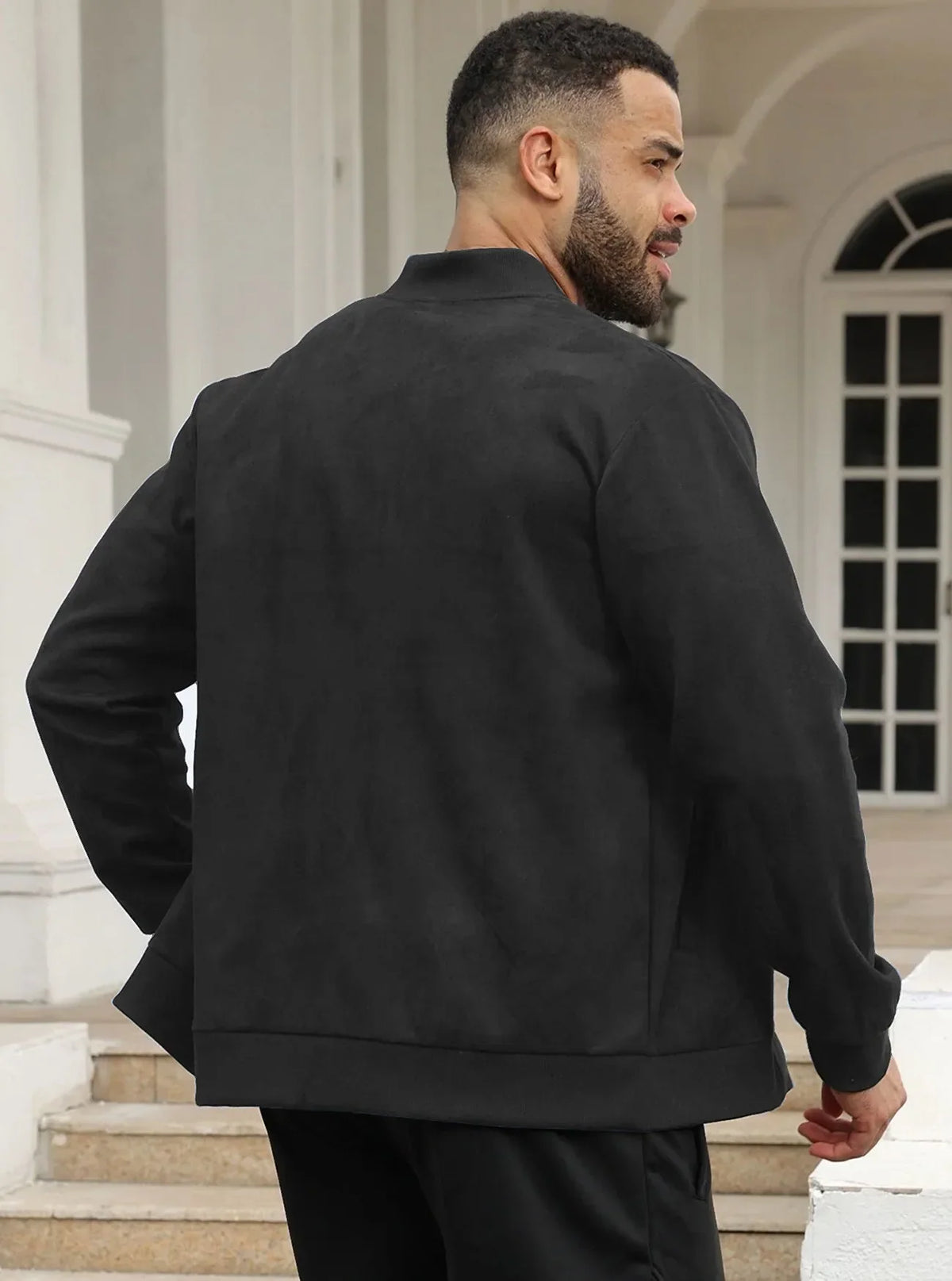 Back view of a man in the black jacket standing on steps by white pillars 20
