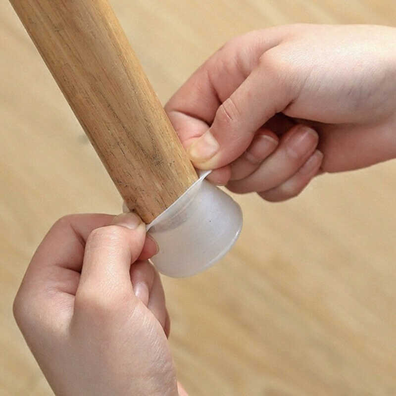 Two hands stretching a translucent silicone cap over the bottom of a wooden furniture leg, showing how it is fitted. 1