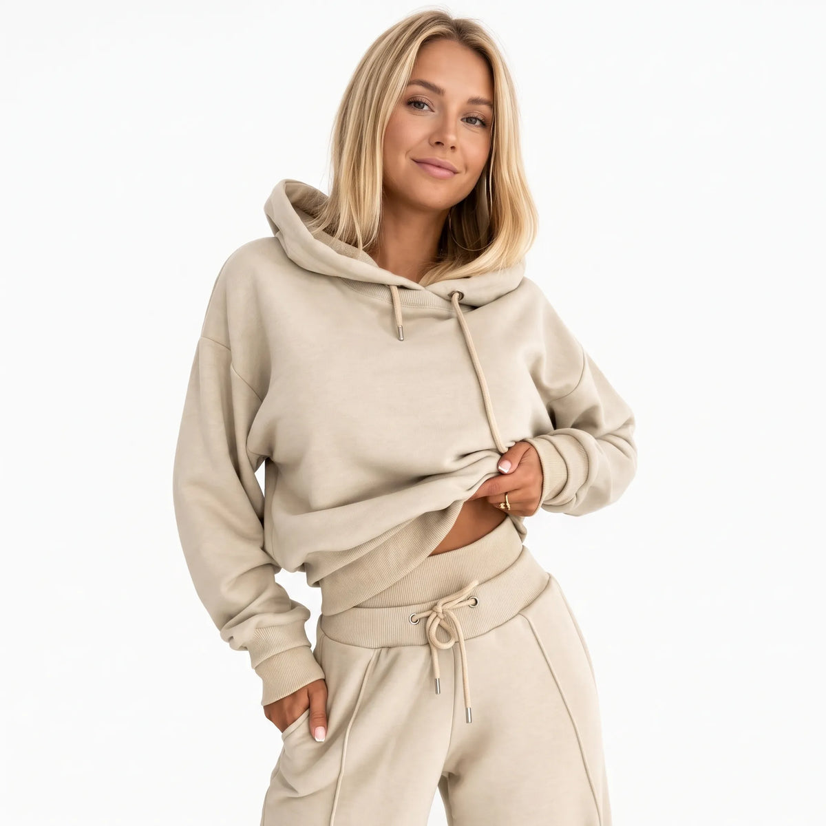 Model in a beige hooded tracksuit with drawstring hood and ribbed cuffs, hand in trouser pocket 21