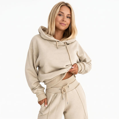 Model in a beige hooded tracksuit with drawstring hood and ribbed cuffs, hand in trouser pocket 21