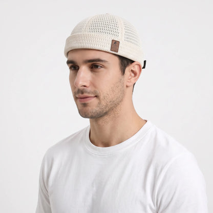 Man in a white t-shirt wearing the cream open weave brimless cap, seen from the front-left 22