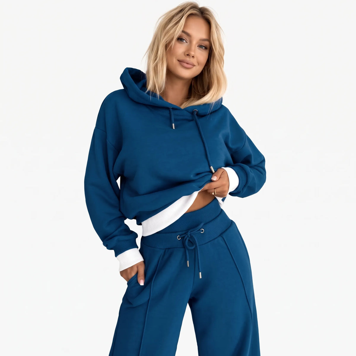 Model wearing the tracksuit in blue with white ribbed hem and cuffs, posed with a hand in her pocket 22