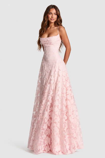 Model in a pale pink raised floral lace gown with draped neckline and thin straps, smiling and looking to the side. 18