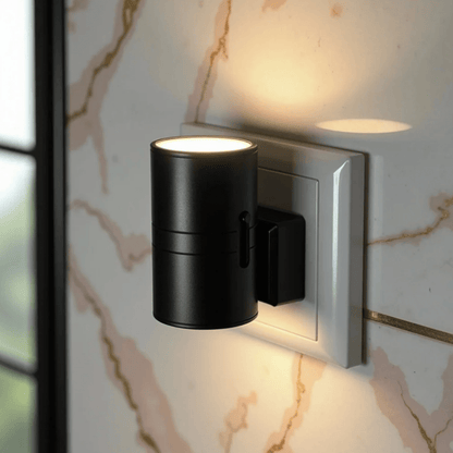 Close-up of a black cylindrical light in a wall socket against pink and gold marble 8