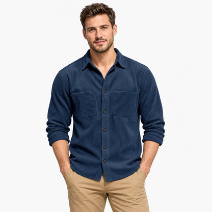 Man wearing the navy blue ribbed corduroy shirt with two chest pockets and rolled sleeves, hands in tan trouser pockets 23