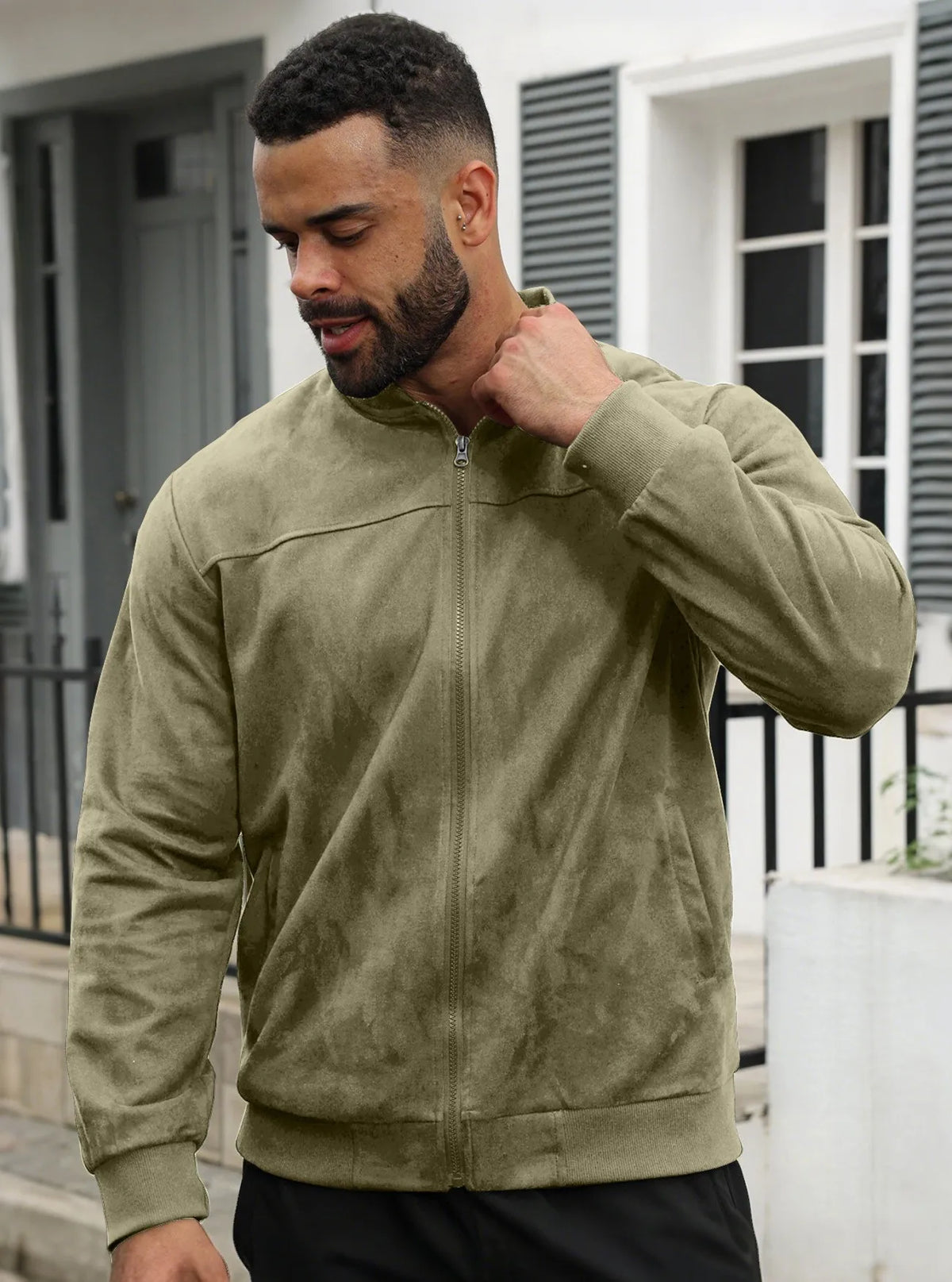 Man wearing the olive green zip-up jacket outdoors, front view, one hand at his collar 23