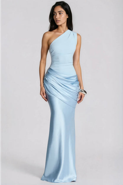 Model in a pale blue one-shoulder maxi dress with draped satin hip panel, looking to the side, wearing a chunky silver cuff. 1