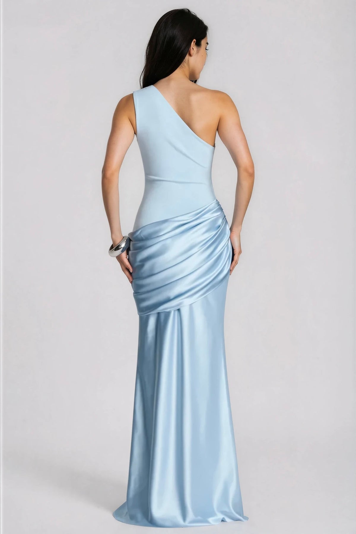 Back view of the pale blue dress, showing the diagonal one-shoulder back, draped satin hip panel and flowing floor-length skirt. 4