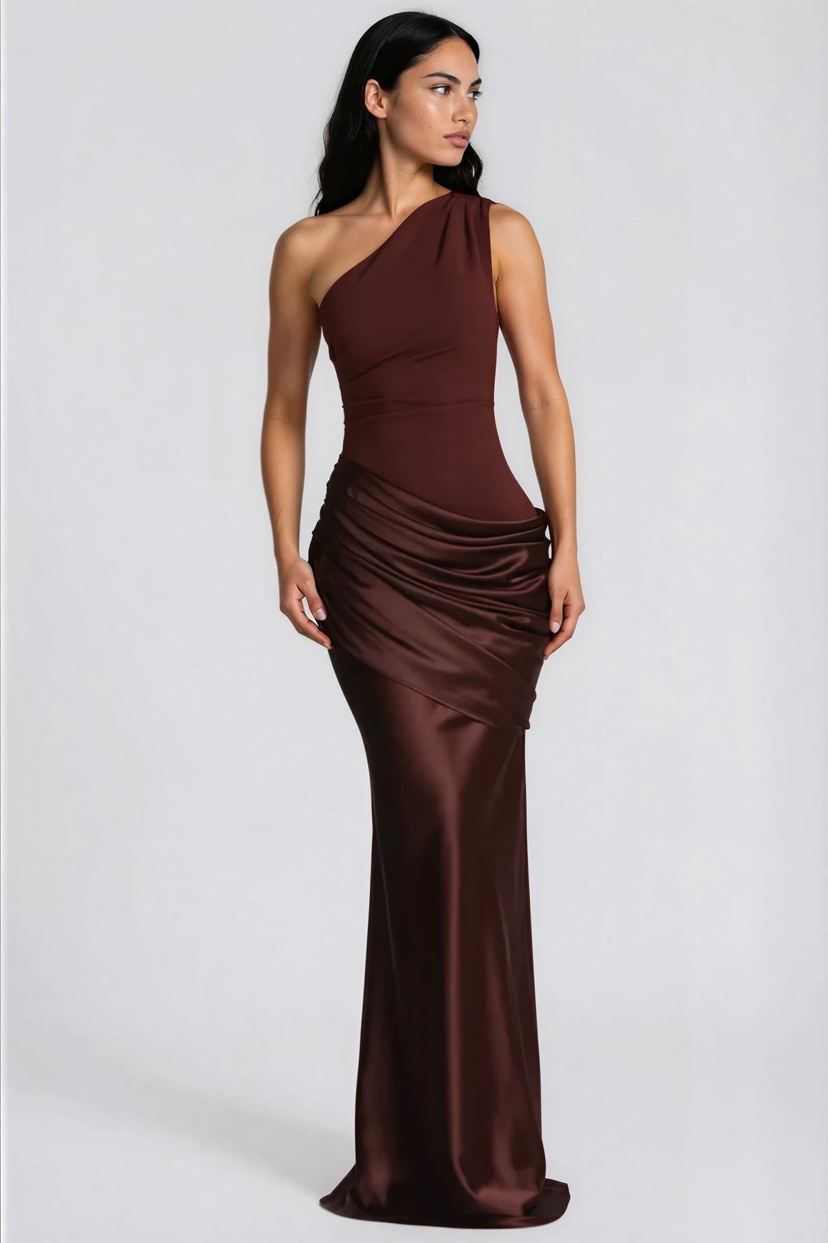 Model in the deep brown version of the dress, turned slightly to the side, showing the glossy draped hip and long skirt. 6