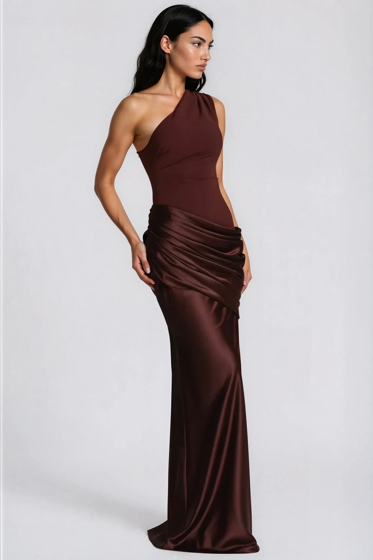 Three-quarter side view of the brown one-shoulder dress, showing the fitted bodice, layered satin drape and floor-length skirt. 8