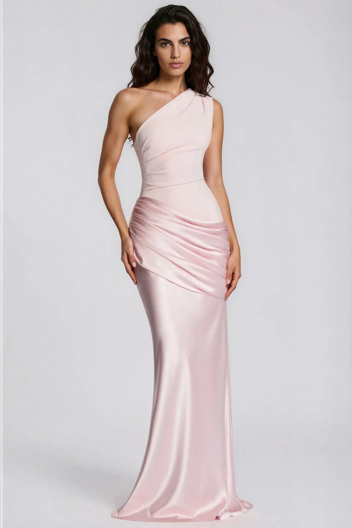 Model wearing the pale pink one-shoulder satin maxi dress with a draped waist, shown from the front with a hand on the hip. 30