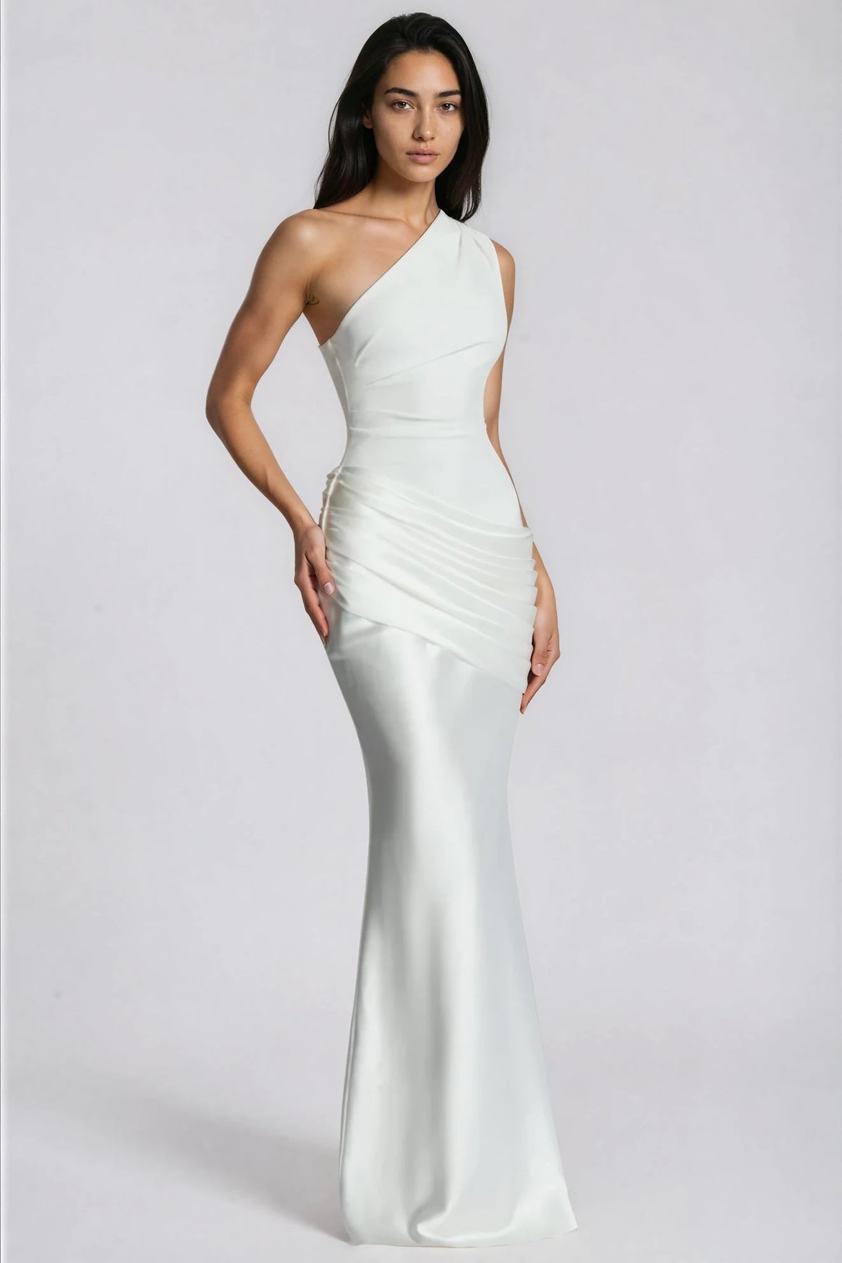 Angled front view of the white dress with one hand on the hip, showing the draped satin panel and slim skirt. 11