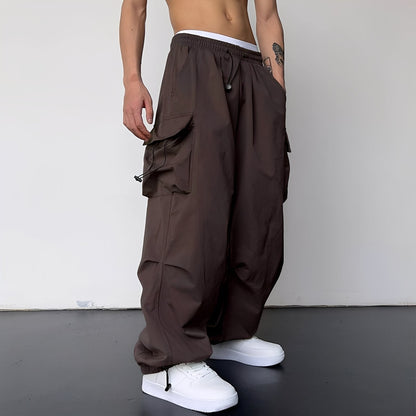 Model wears the baggy cargo trousers in dark brown with white trainers, side view 6
